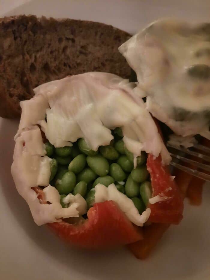 Tomato filled with green beans and topped with creamy dressing, creating a bizarre and unappetizing.