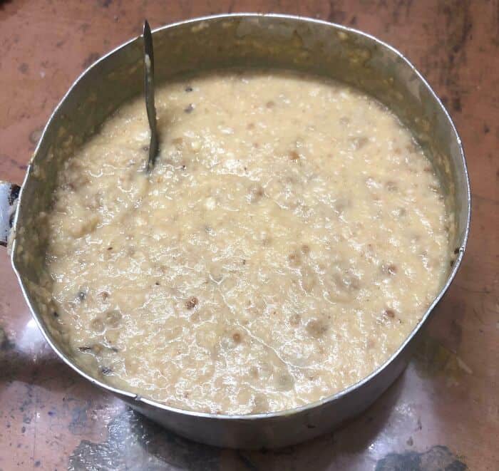 Uncooked, lumpy food in a metal bowl with a spoon, related to cursed food.