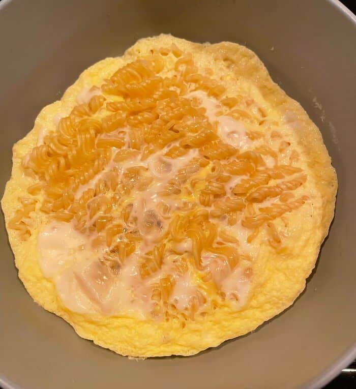 Close-up of cheesy scrambled eggs on a plate, with melted cheese on top.