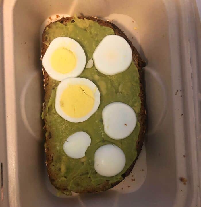 Unusual avocado toast topped with sliced hard-boiled eggs, creating a bizarre and unappetizing appea.