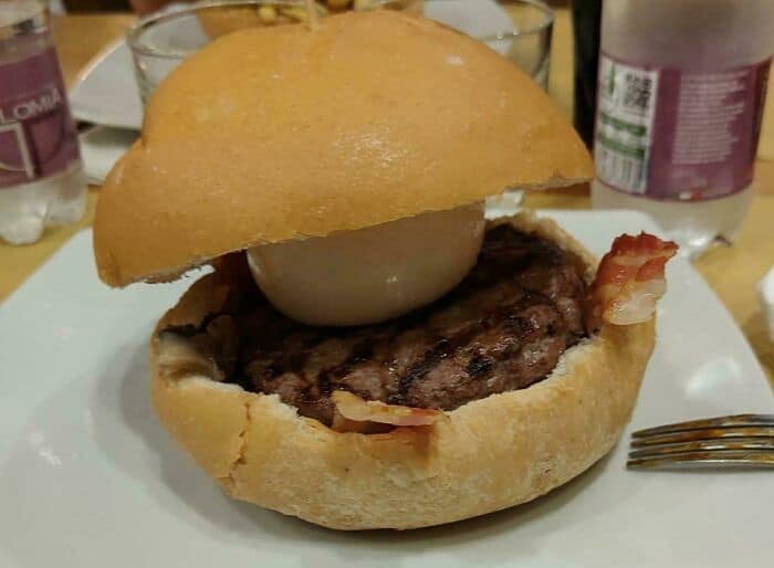 Unusual burger with a large onion and meat patty in a bun.
