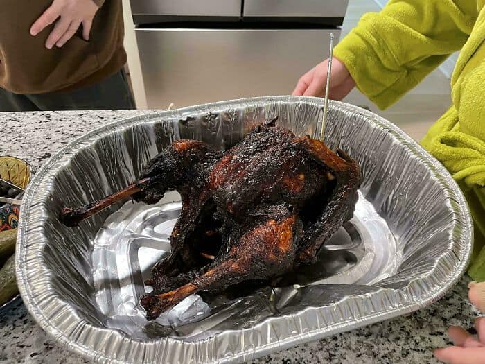 Charred whole chicken, roasted to perfection, served on a foil tray for a humorous take on cursed fo.