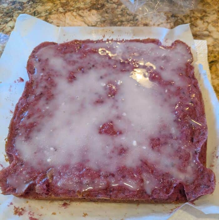 Close-up of a fried Spam slice with a white glaze on top, on parchment paper.