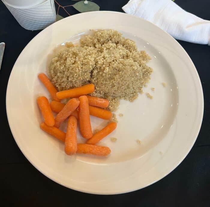 Quinoa and baby carrots served on a white plate, labeled as cursed food.