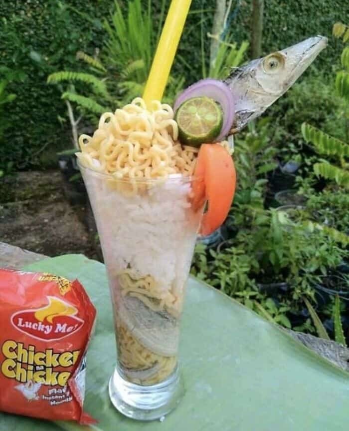 Fish with noodles and vegetables in a glass, bizarre food presentation.