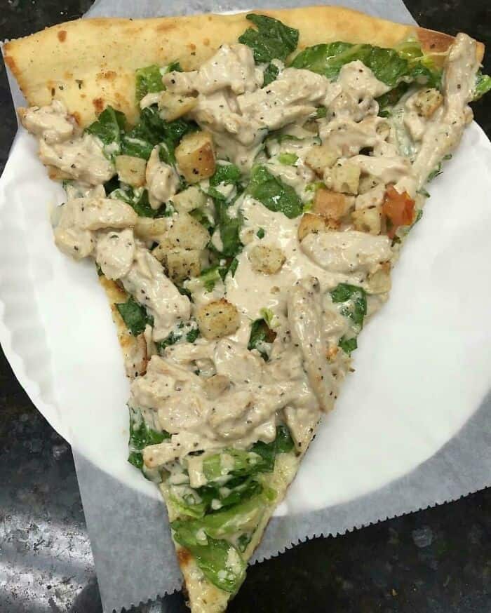 Delicious pizza slice topped with creamy chicken, fresh greens, and vegetables. Perfect for a savory.
