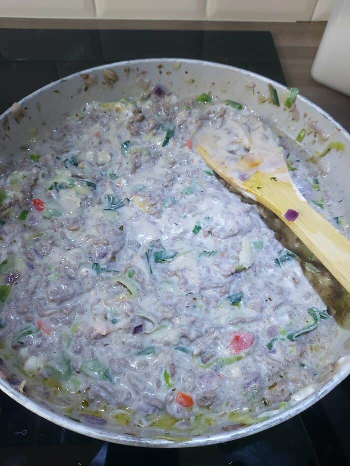 Unappealing, lumpy mixture of food with strange colors and textures in a frying pan.