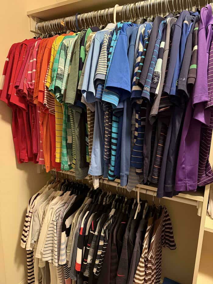 Colorful organized clothing rack with striped and solid shirts in various shades.