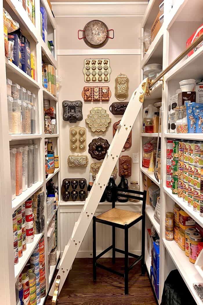 Neatly organized pantry with shelves, jars, and a step ladder for easy access.