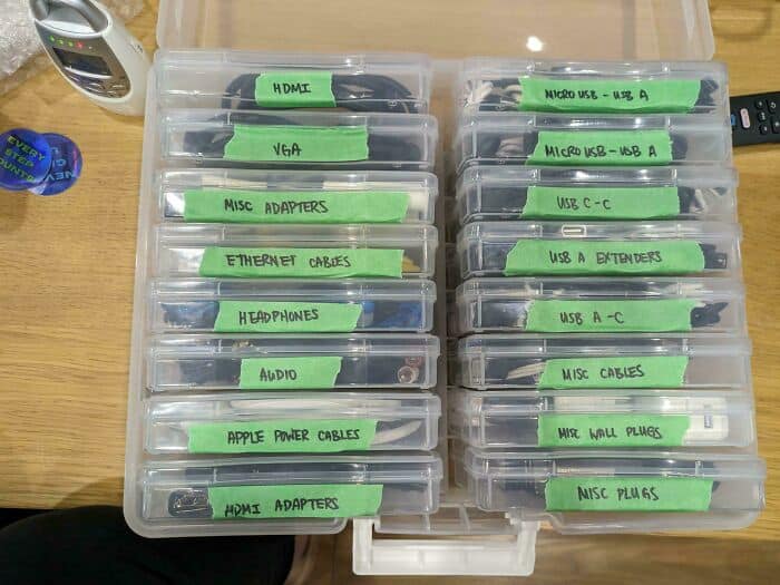 Neatly organized tech cables and adapters in labeled plastic containers.