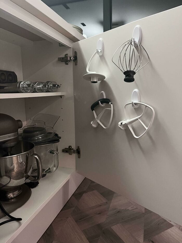 Hanging kitchen utensils on cabinet door for organized storage and easy access.