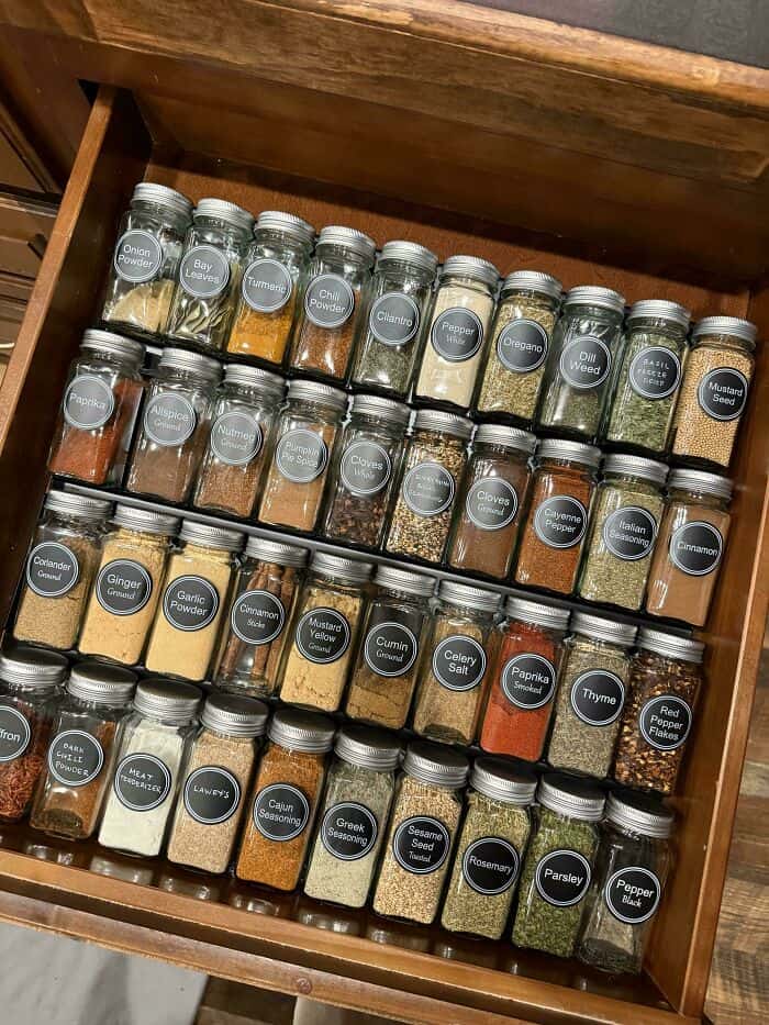 Spice jars neatly arranged in a wooden drawer for easy access and organization. Perfect for a tidy a.