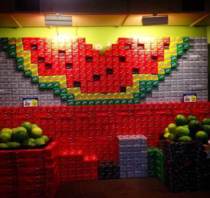 Watermelon wall made of stacked boxes with real watermelons at the base.