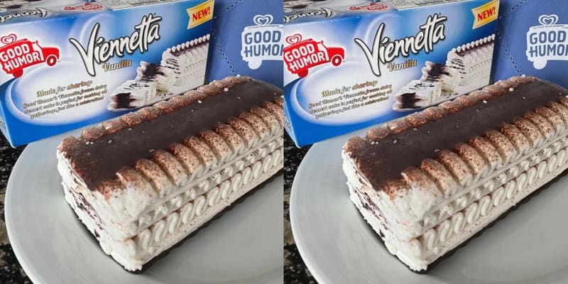 Cream-filled chocolate roll cake with chocolate drizzle on top, placed on a gray surface.