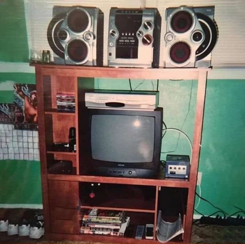 Vintage stereo system with speakers, a TV, and a gaming console on a wooden shelf.
