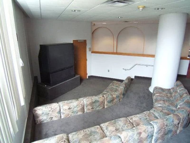 Small lounge area with a large TV, patterned couches, and a white wall with decorative arches.