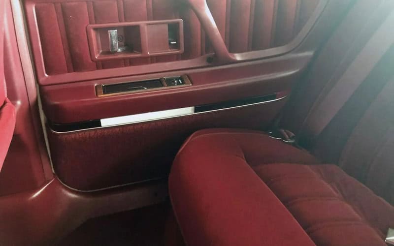 Vintage car interior with red upholstery and wood paneling.