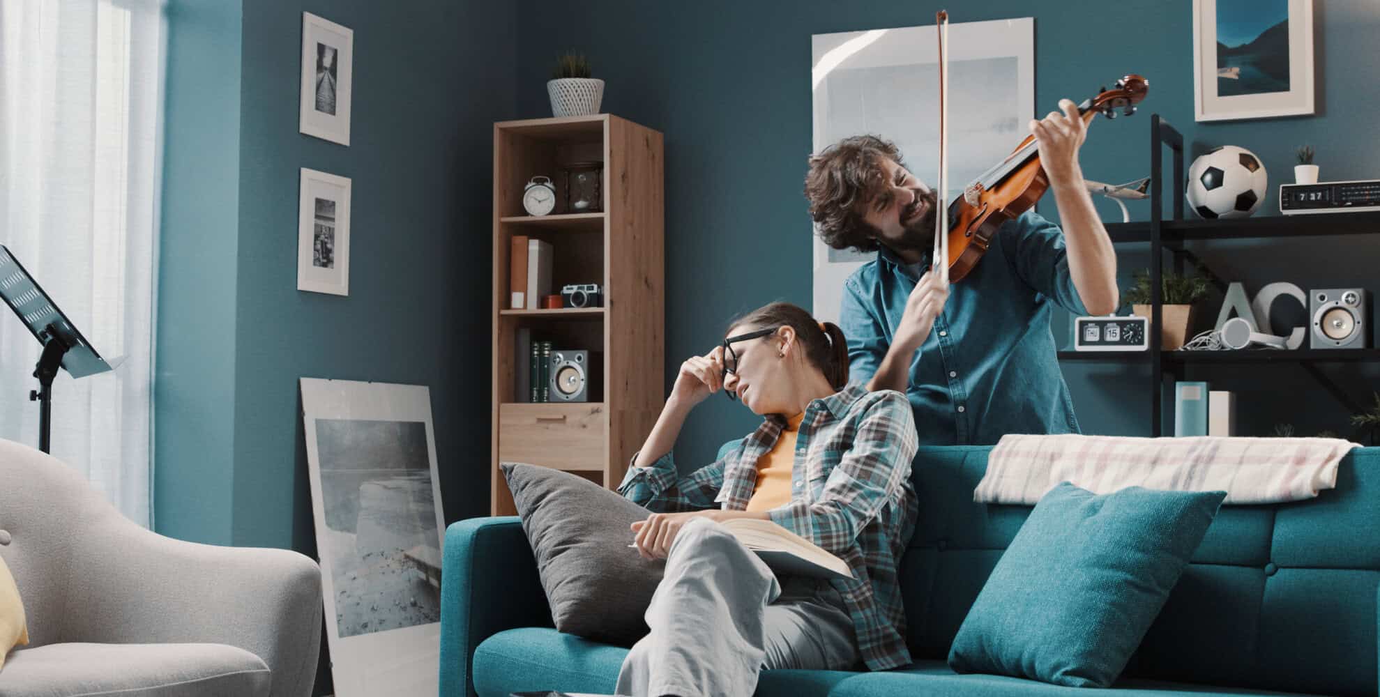 Two roommates playing guitar and reading in a cozy living room.