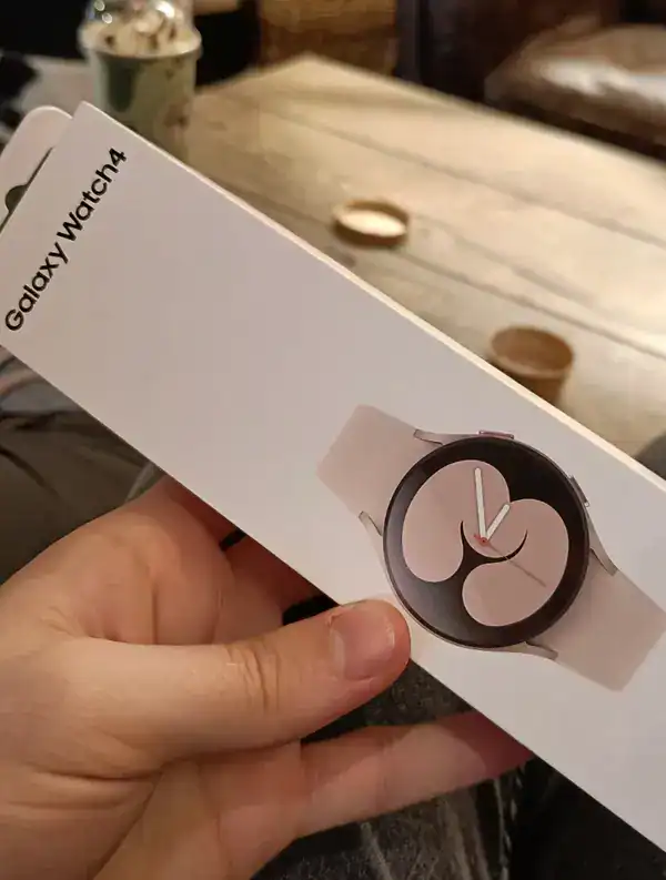 Galaxy Watch4 smartwatch in hand, showing its round face and sleek design.
