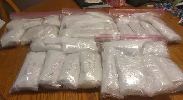 Multiple sealed plastic bags containing unknown substances on a wooden surface.