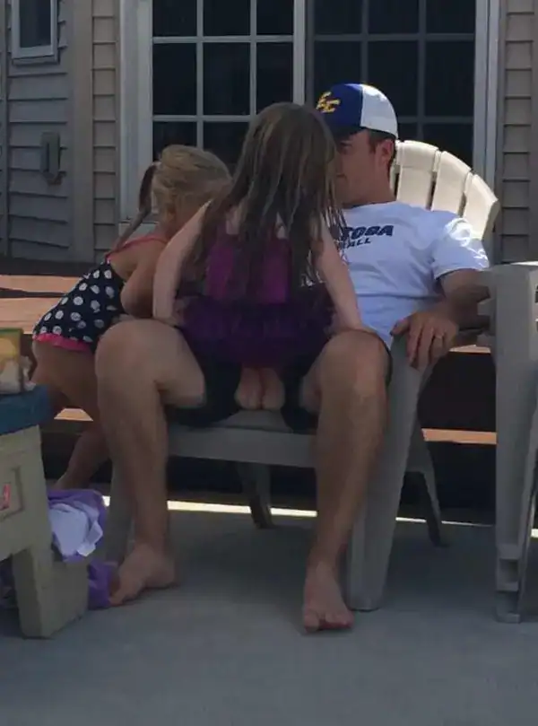 Family enjoying a sunny day outside on the porch with kids sitting on dad's lap.