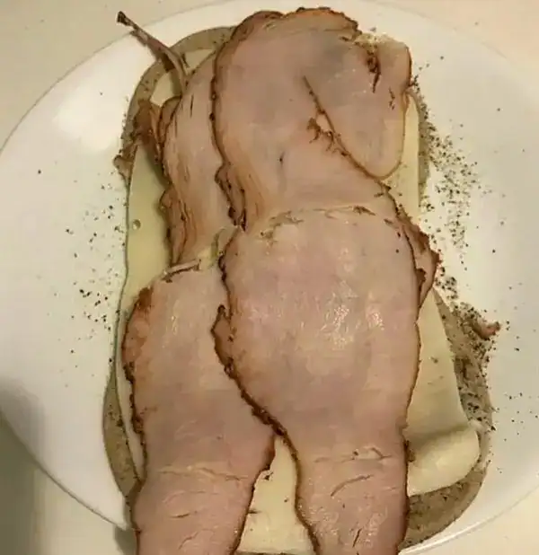 Delicious roast beef slices on a bun with seasoning, served on a white plate. Perfect for a hearty m.