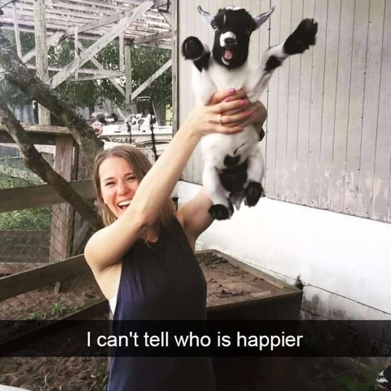 Woman holding a happy black and white puppy outdoors.