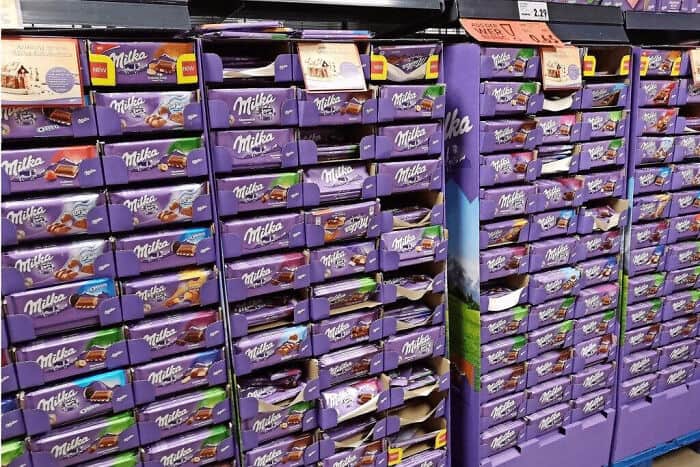 Milka chocolate bars on store shelves in purple packaging.