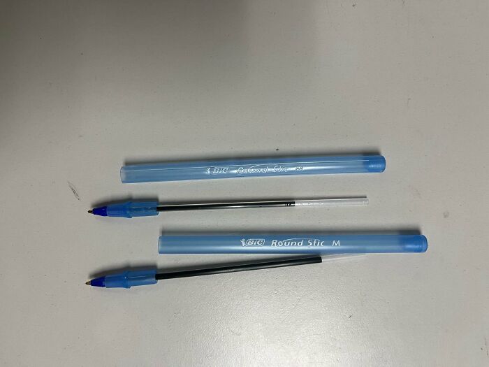 Three blue pens with black ink on a white surface.