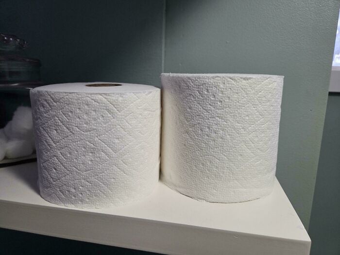 Toilet paper rolls on a white shelf against a green wall.