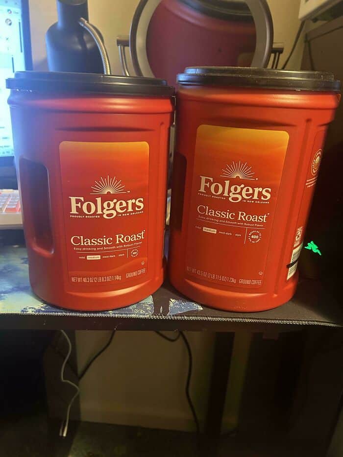 Folgers Classic Roast coffee containers on a desk with a computer and other items in the background.