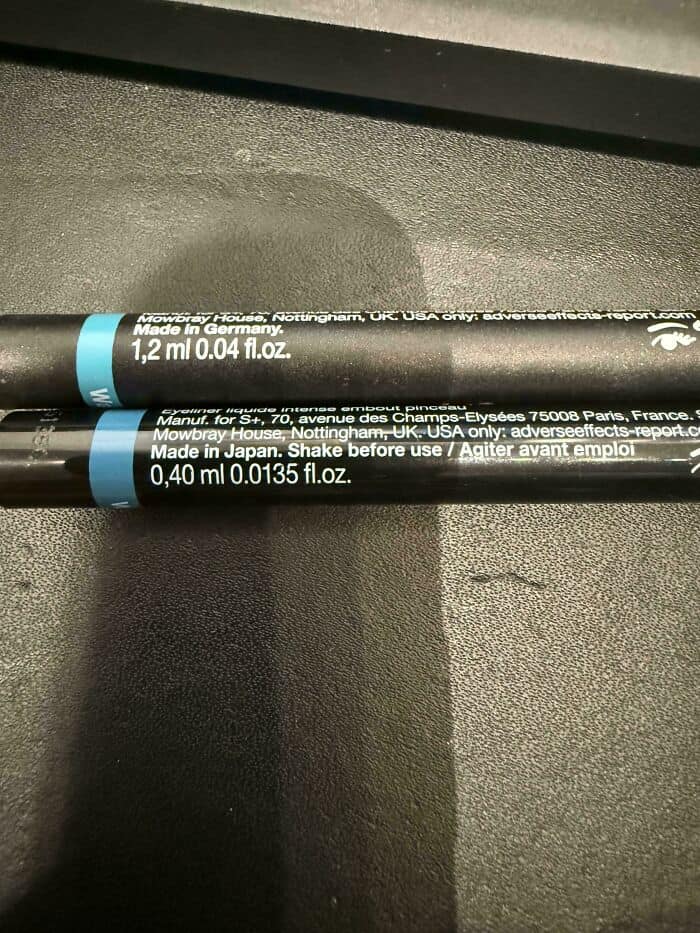 Lip gloss tubes on a black surface with product details and instructions.