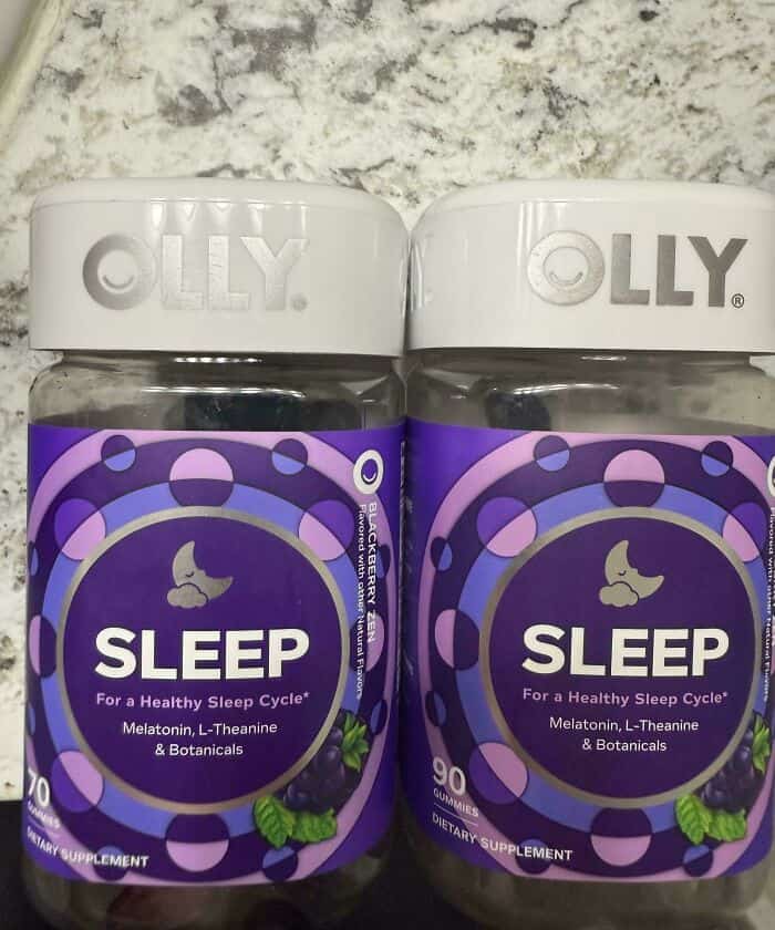 Melatonin sleep aid bottles with purple labels and white caps, placed on a marble surface.