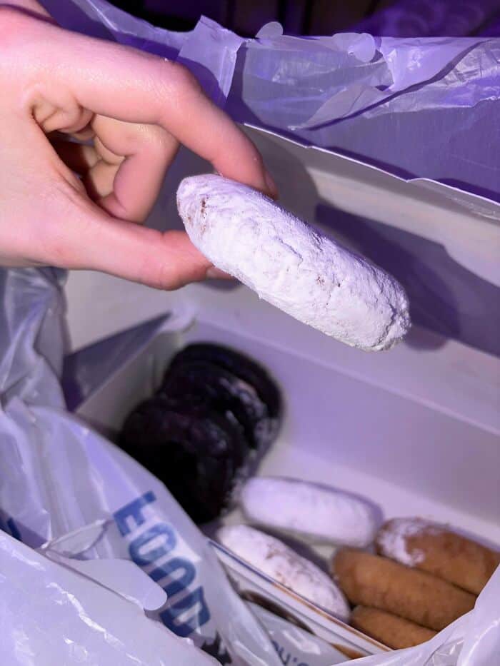 Hand holding a white ice cream bar with a purple background.