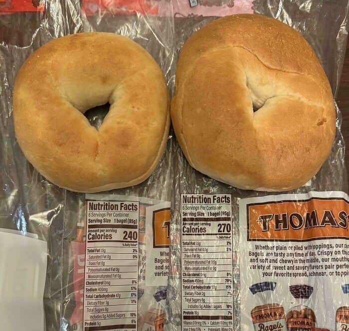 Fresh bagels with nutrition labels and a Thomas bagel bag on a wooden surface.