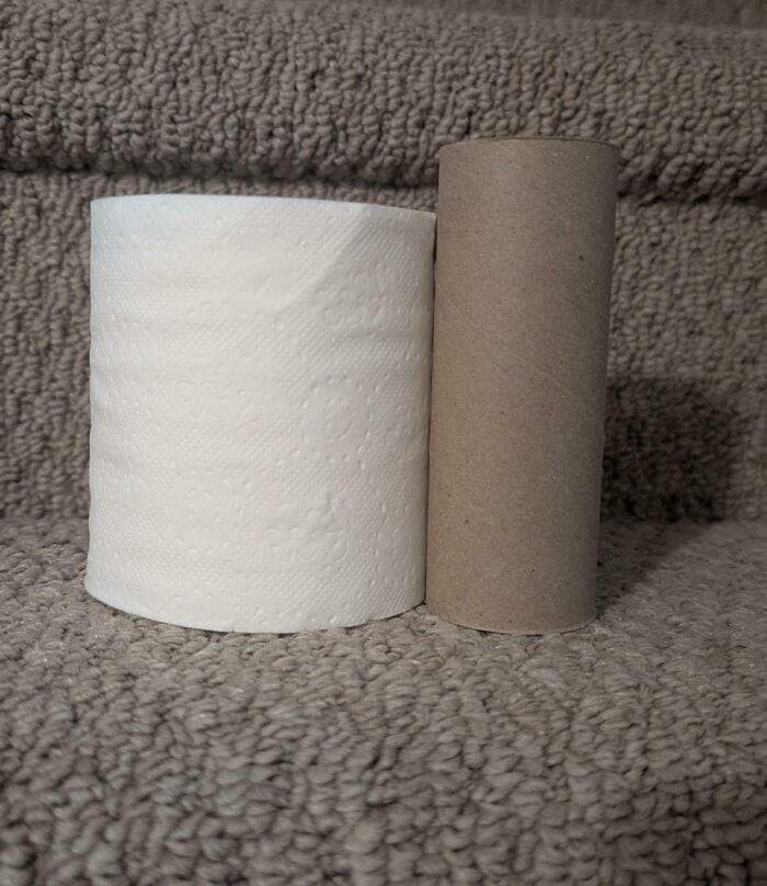 Toilet paper rolls on a textured surface with a towel in the background.