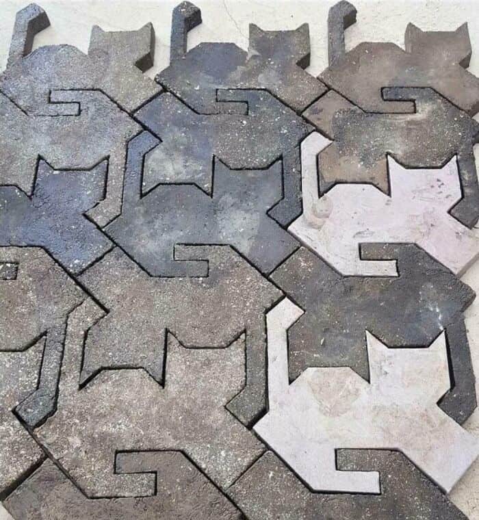 Interlocking concrete pavers in gray and light beige colors arranged in a pattern.