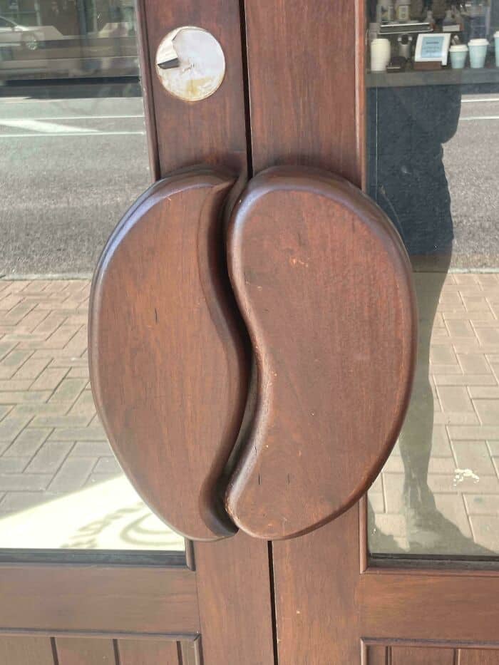 A door handle shaped like a coffee bean on a wooden door.