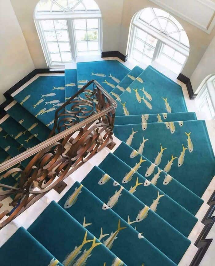 Bright blue staircase carpet with yellow fish pattern, viewed from the top looking down.