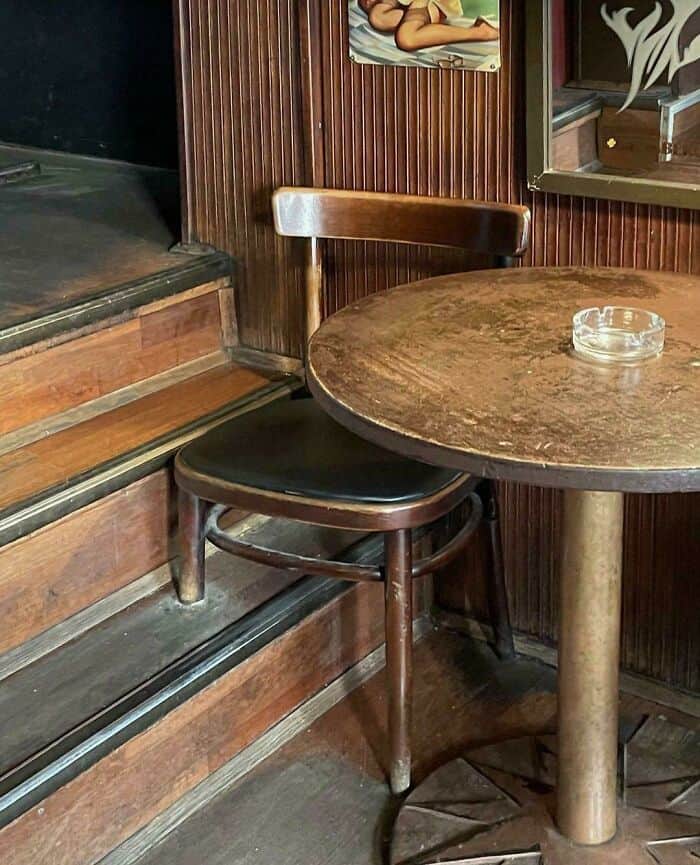 Wooden chair and round table with ashtray in a cozy cafe setting.