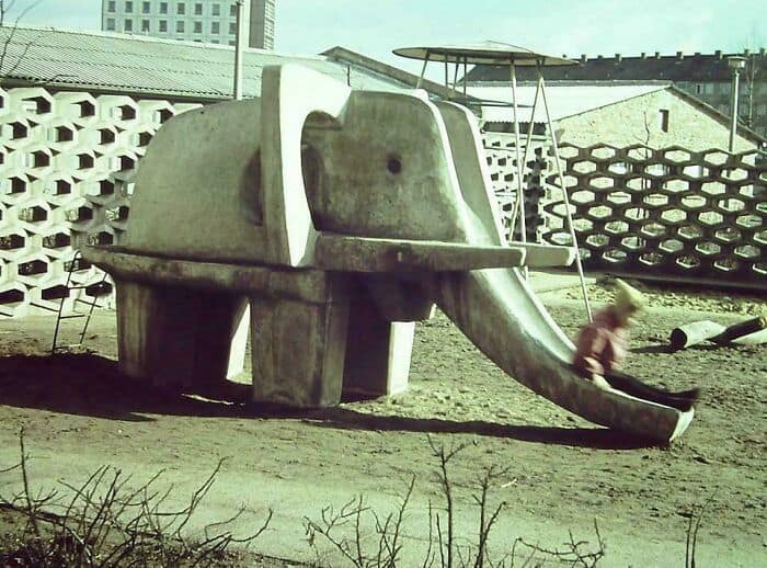 Concrete playground slide shaped like an elephant in an outdoor area.