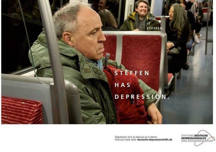 A man with gray hair and a green jacket sitting on a bus, looking tired and sad.