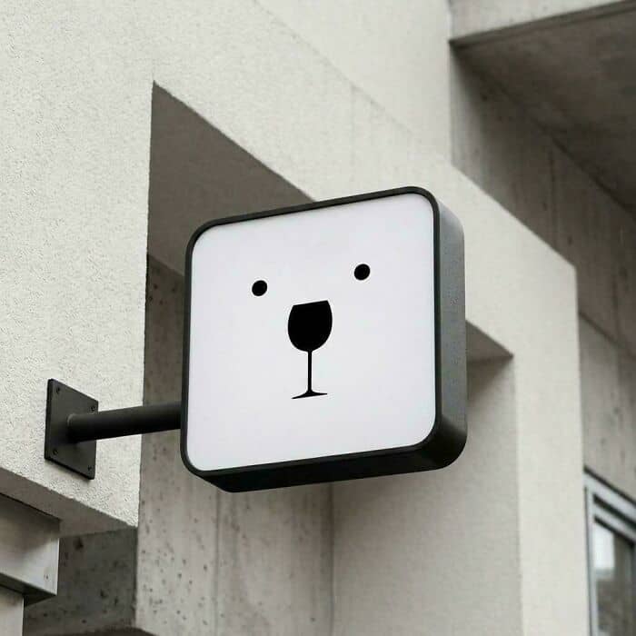 Sign with a bear face illustration on a building wall.