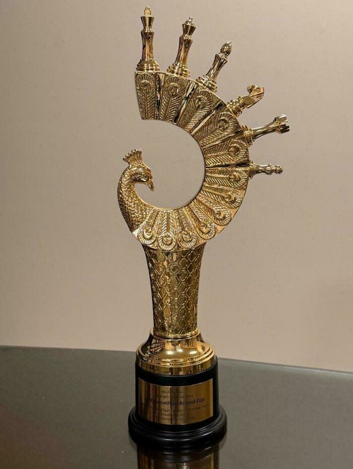 Golden peacock-shaped trophy with a curved body and multiple small peacocks on top.