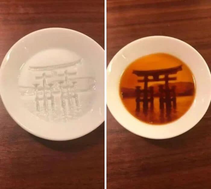 White bowl with water and a bowl with tea showing a torii gate reflection.