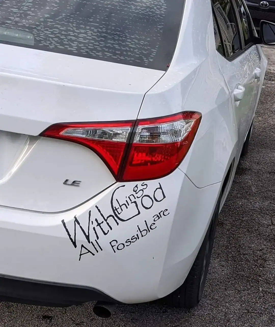 Car with a handwritten message reading "Without things good all are possible" on the rear bumper.
