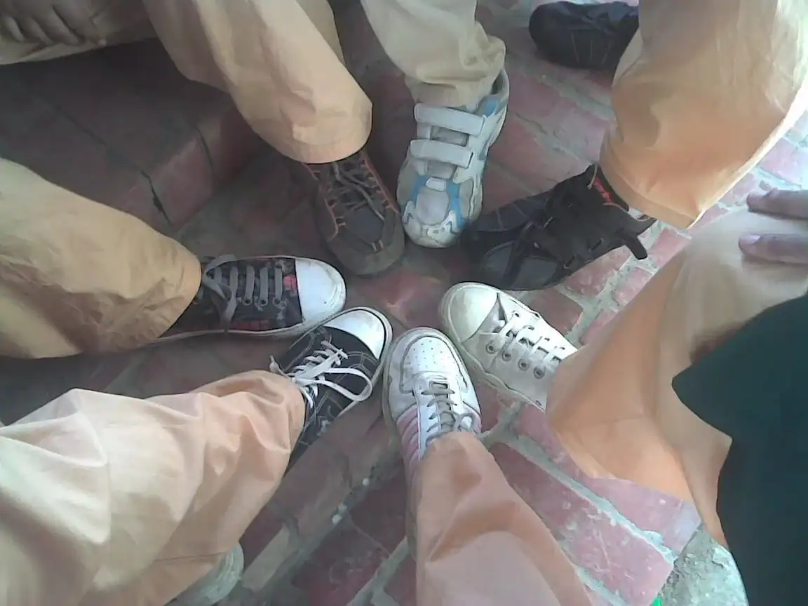 Group of people wearing various casual sneakers standing in a circle.