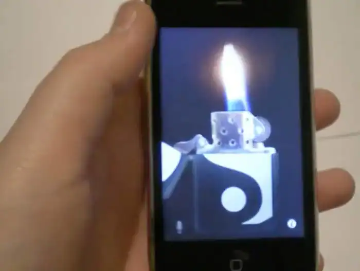 Hand holding a phone with a lighter flame appearing on the screen.