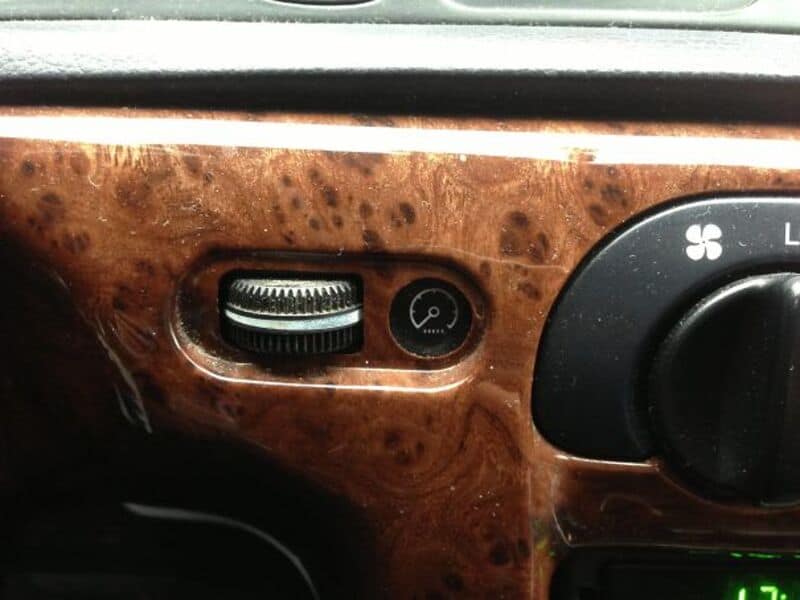 Vintage car dashboard with wood grain finish and climate control knob.