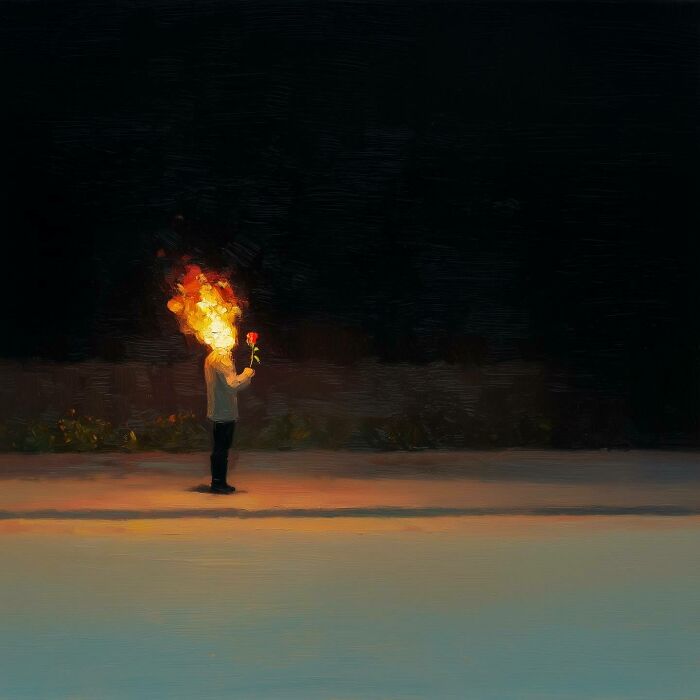 Man holding a lit torch with flames, standing on a dark street at night.